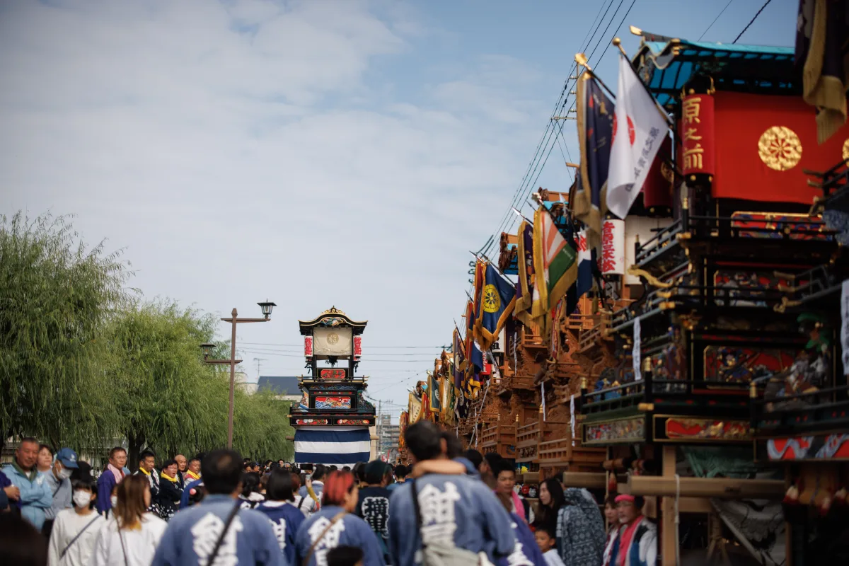 通り沿いに並ぶ西条祭りのだんじりの列と、法被姿で行き交う人たち