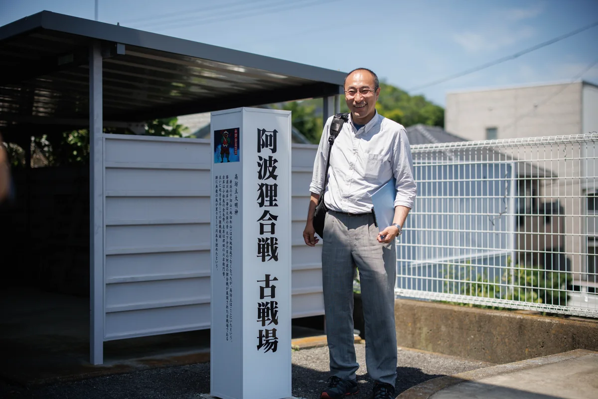 阿波狸合戦 古戦場の案内板の前に立つ男性