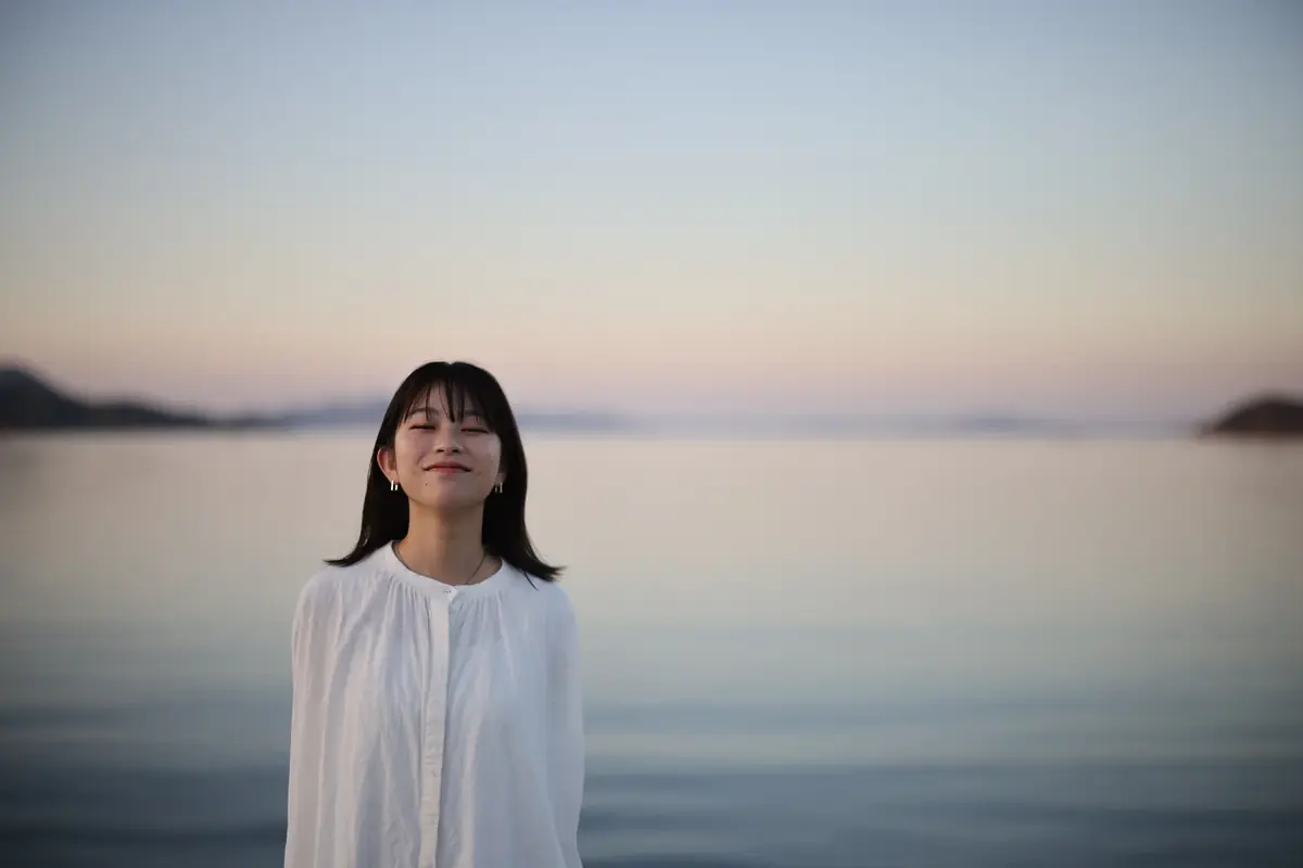 夕暮れの海辺に立つ人