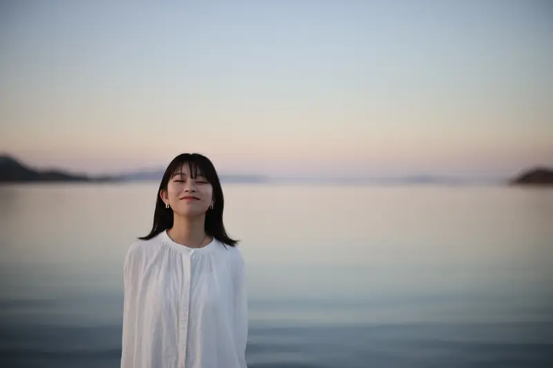 夕暮れの海辺に立つ人