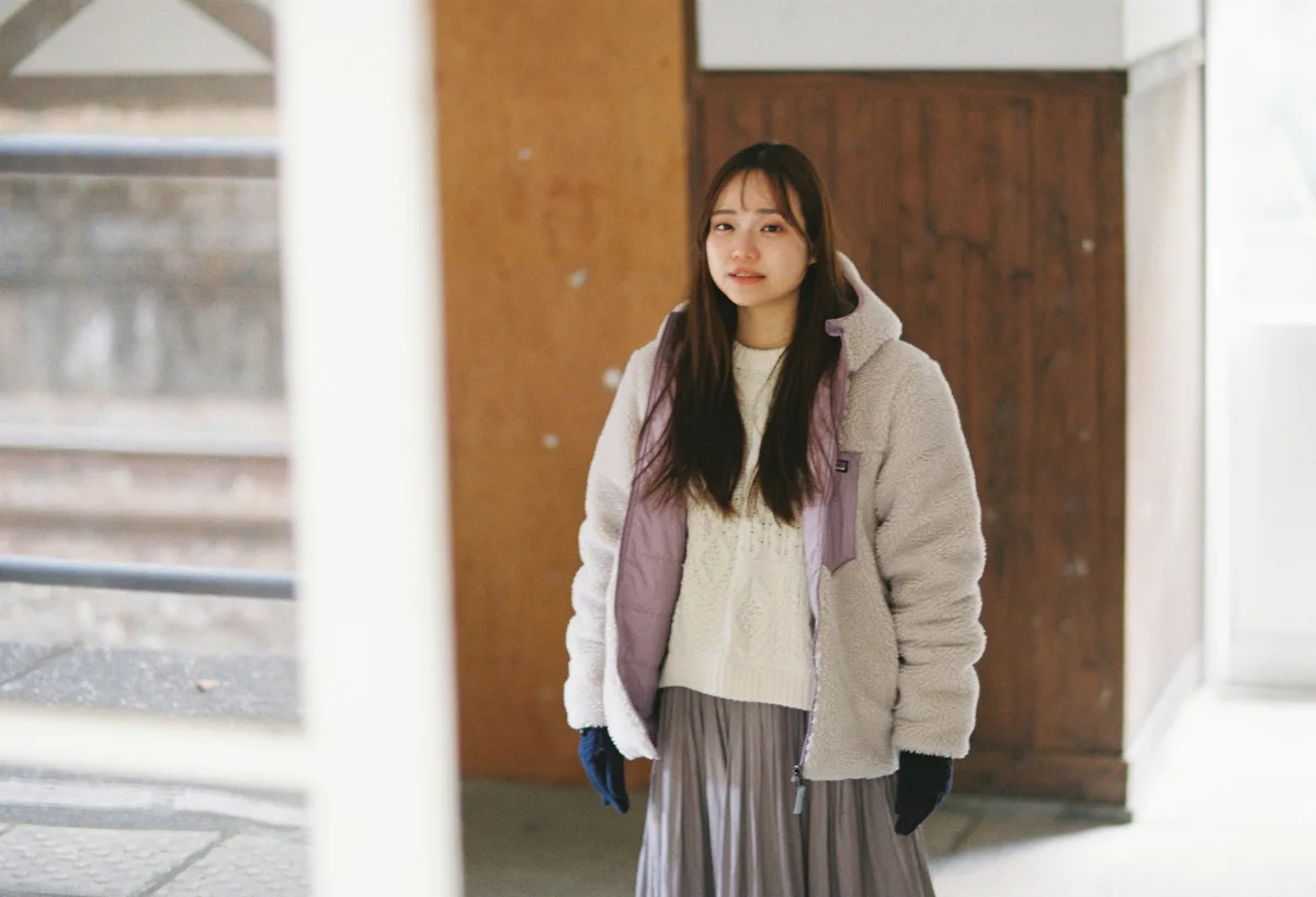 駅舎の木の扉の前に立つ女性