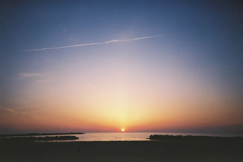 日本海に沈む夕日と飛行機雲