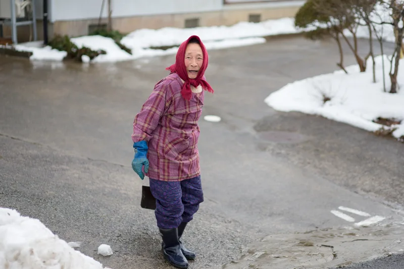 雪の残る道で振り返る、赤い頭巾の女性