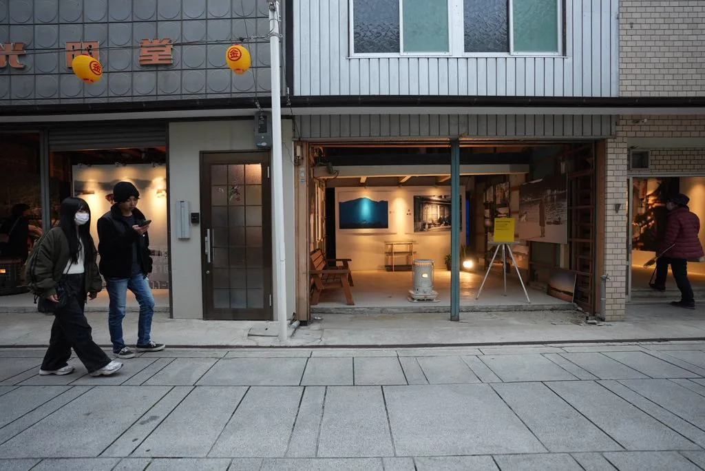 通りから見た会場。開け放した入口の奥に写真が並び、人が行き交う