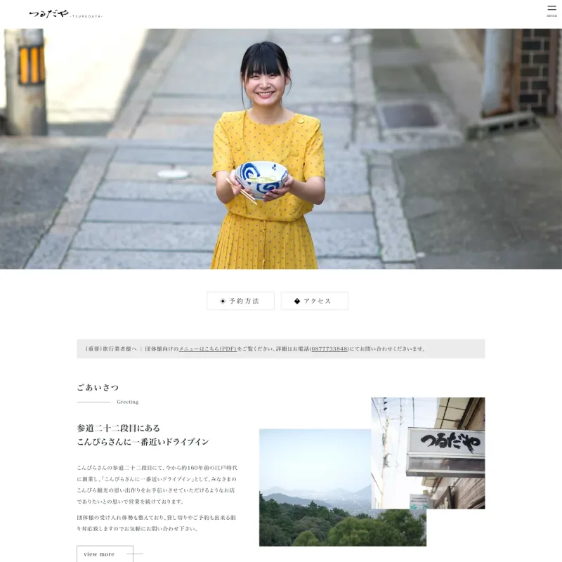 つるだやのWebサイト。参道でうどんの丼を持つ人物、店舗紹介、メニュー、アクセスを掲載したトップページ上部